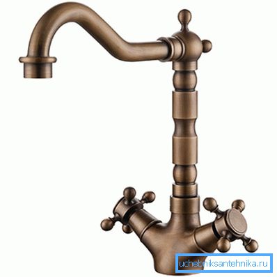 Das Foto zeigt einen klassischen Retro-Wasserhahn mit einer markanten, hohen und komplizierten Form des Auslaufs. Das Foto zeigt einen klassischen Retro-Wasserhahn mit einer markanten, hohen und komplizierten Form des Auslaufs.