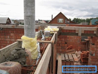 Das Foto zeigt den Einbau von Asbestzementrohren in die tragende Ziegelmauer.